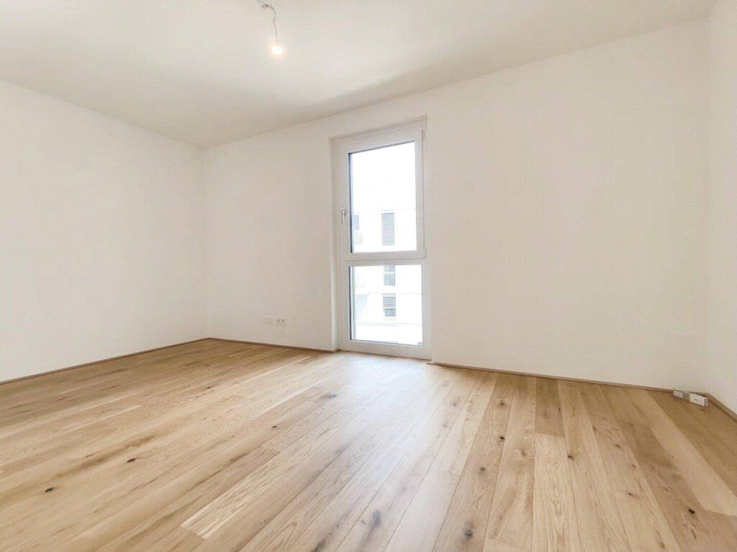 Modernes, leeres Schlafzimmer mit hellem Holzfußboden und weiß gestrichenen Wänden, sehr gepflegt.