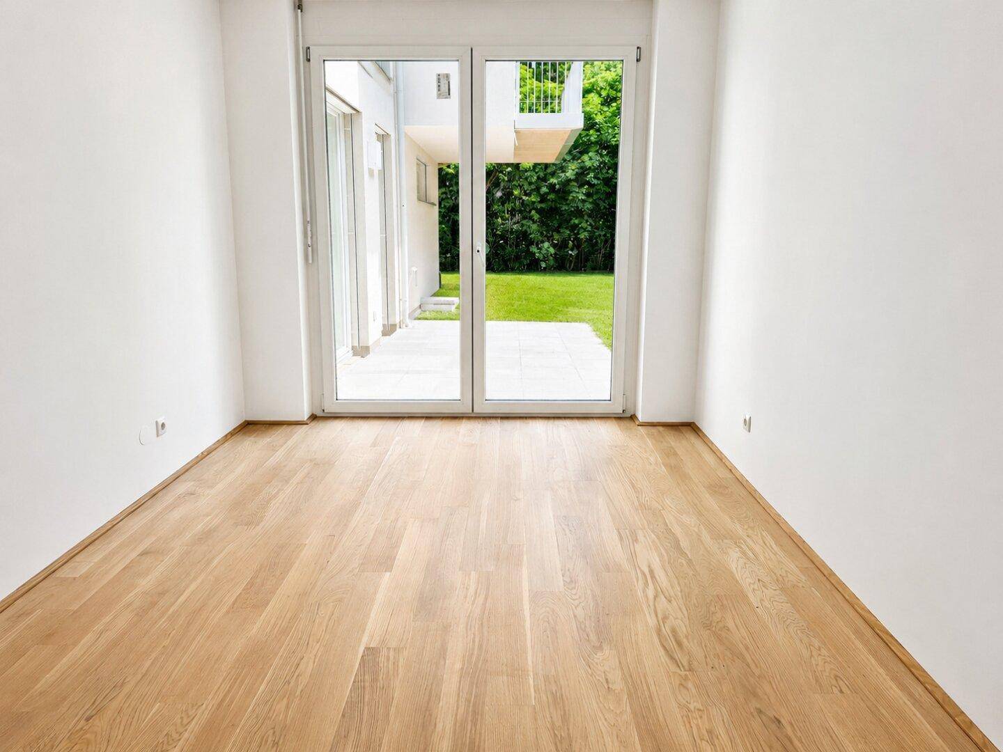 Helles Zimmer mit Parkettboden und direktem Zugang zur Außenterrasse und Garten.