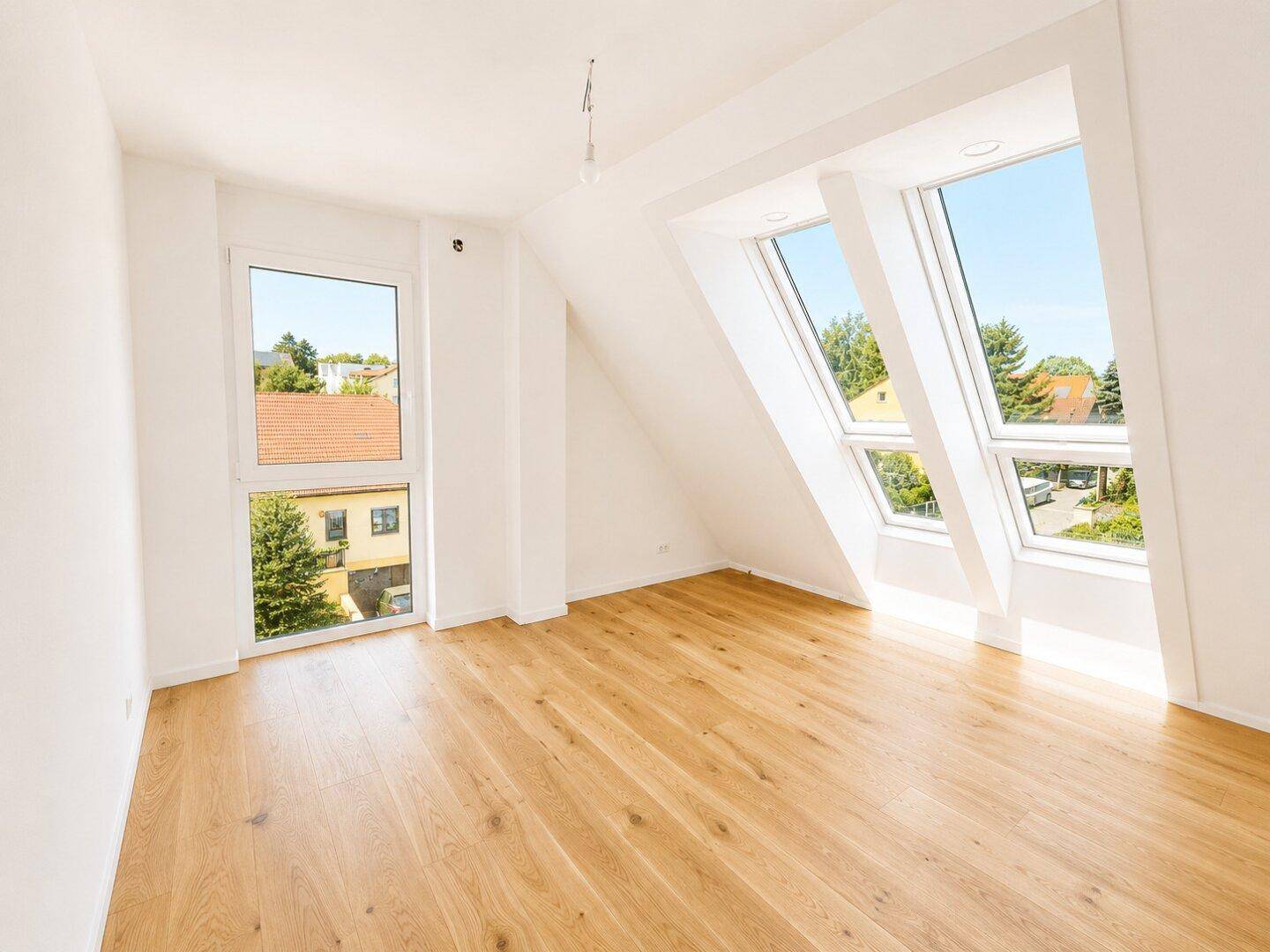 Lichtdurchfluteter Raum im Dachgeschoss mit Holzboden und mehreren Dachfenstern, ideal als Schlafzimmer.