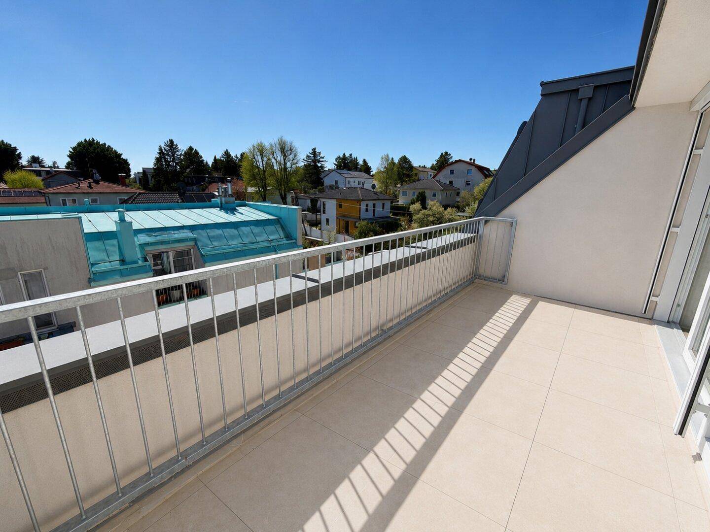 Sonniger Balkon mit Fliesenboden und stabilem Metallgeländer, ideal zum Entspannen im Freien mit Aussicht.