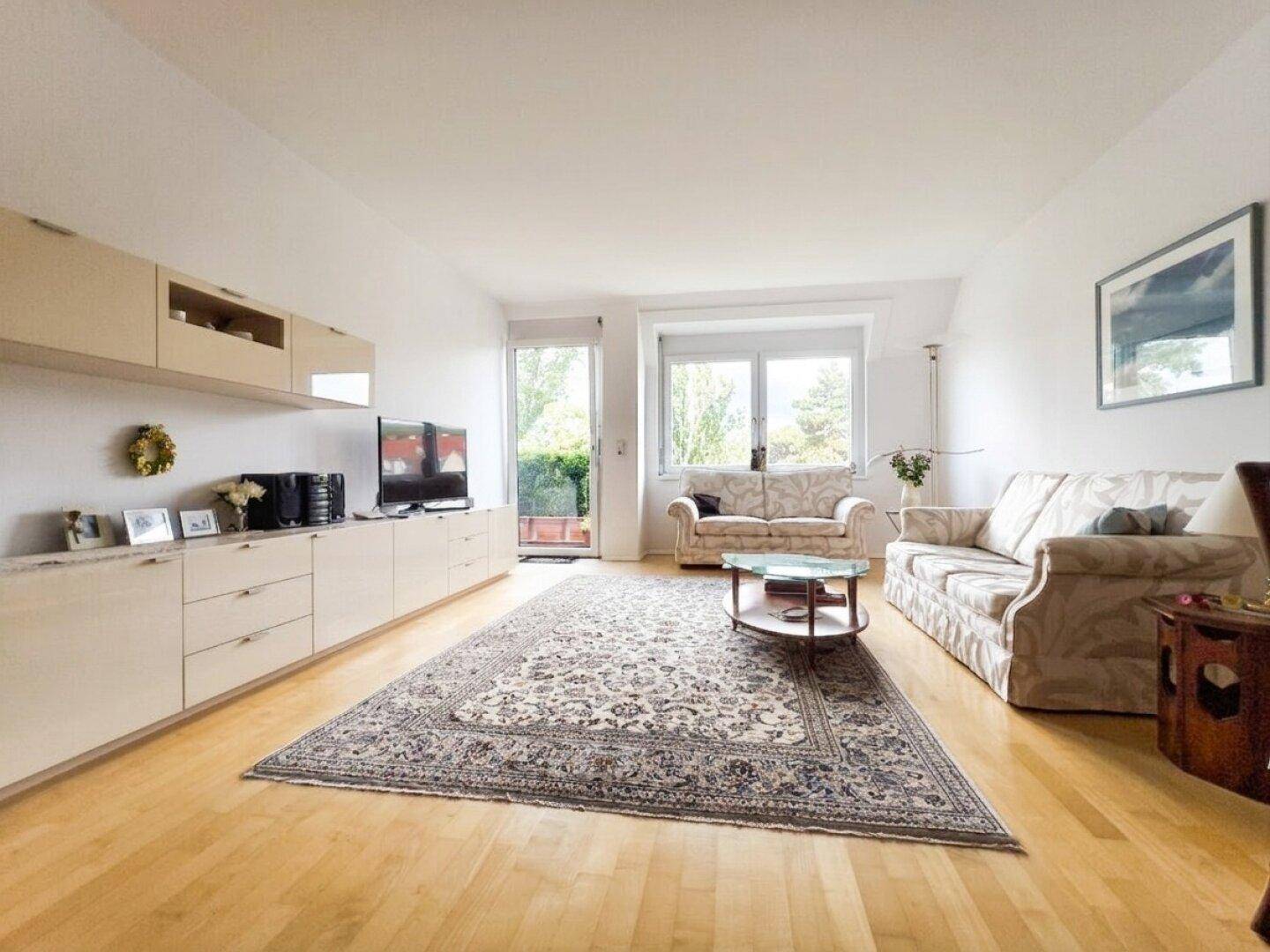 Geräumiges Wohnzimmer mit Holzparkett, großem Teppich und moderner TV-Möbelwand.