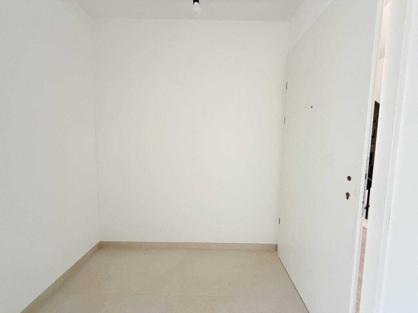 Heller Eingangsbereich mit Fliesenboden und weißer Tür, der in die Wohnung führt.