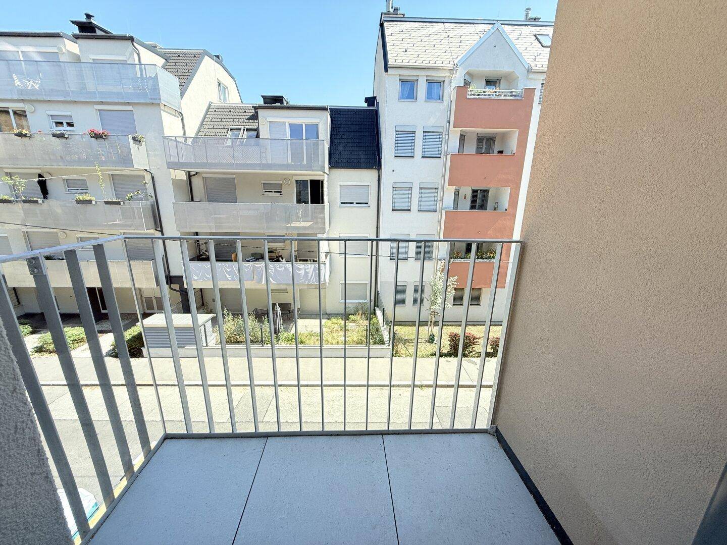 Kleiner Balkon mit Fliesenboden und Metallgeländer, bietet einen Blick auf den Innenhof.