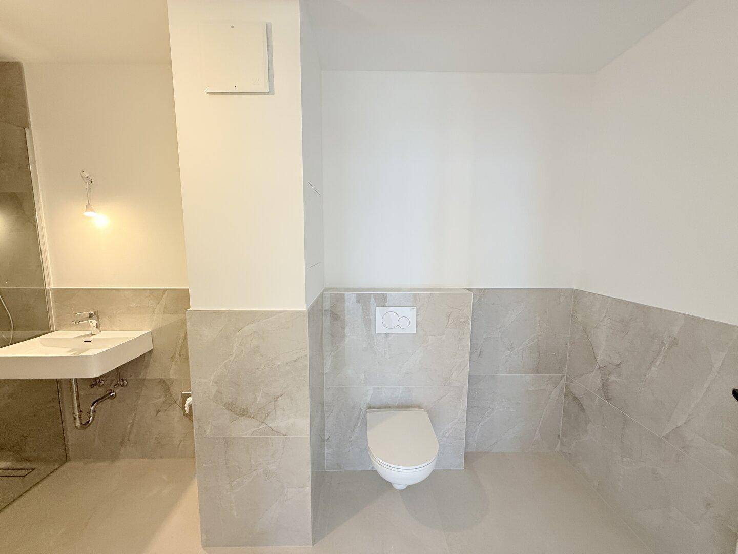 Zeitgemäßes Badezimmer mit Wand-WC, großformatigen Fliesen und modernem Design.