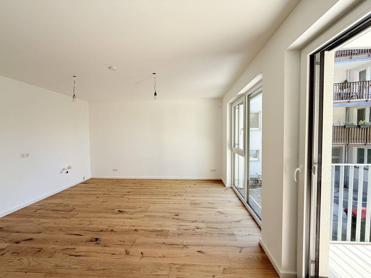 Heller Raum mit Holzboden und direktem Zugang zu einem Balkon, ideal für frische Luft und Entspannung.