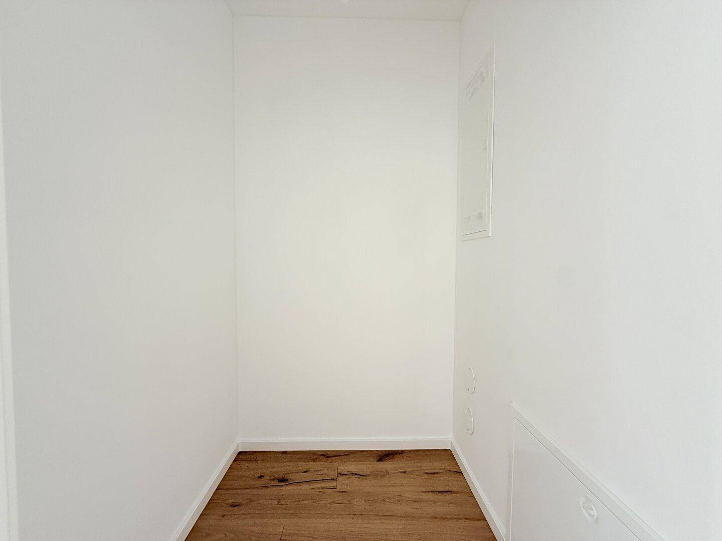 Kleiner Abstellraum mit Holzboden und weißen Wänden, ideal für zusätzlichen Stauraum und Haushaltsgeräte.