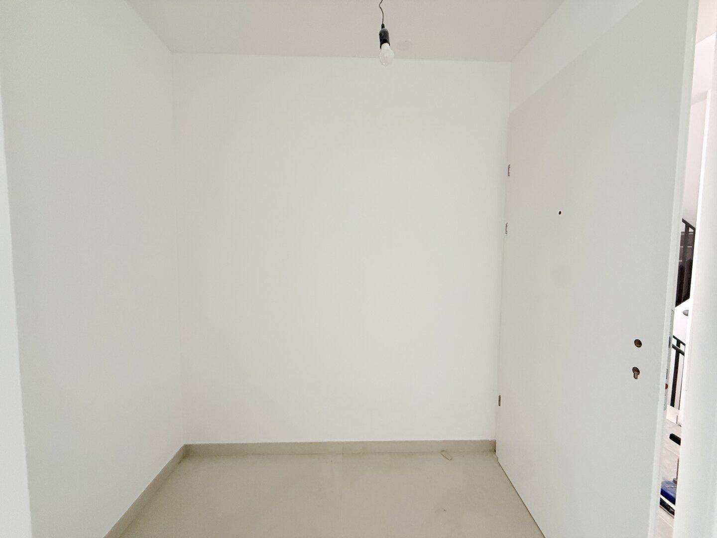 Eingangsbereich mit Fliesenboden und weißer Eingangstür, bietet einen klaren Übergang.
