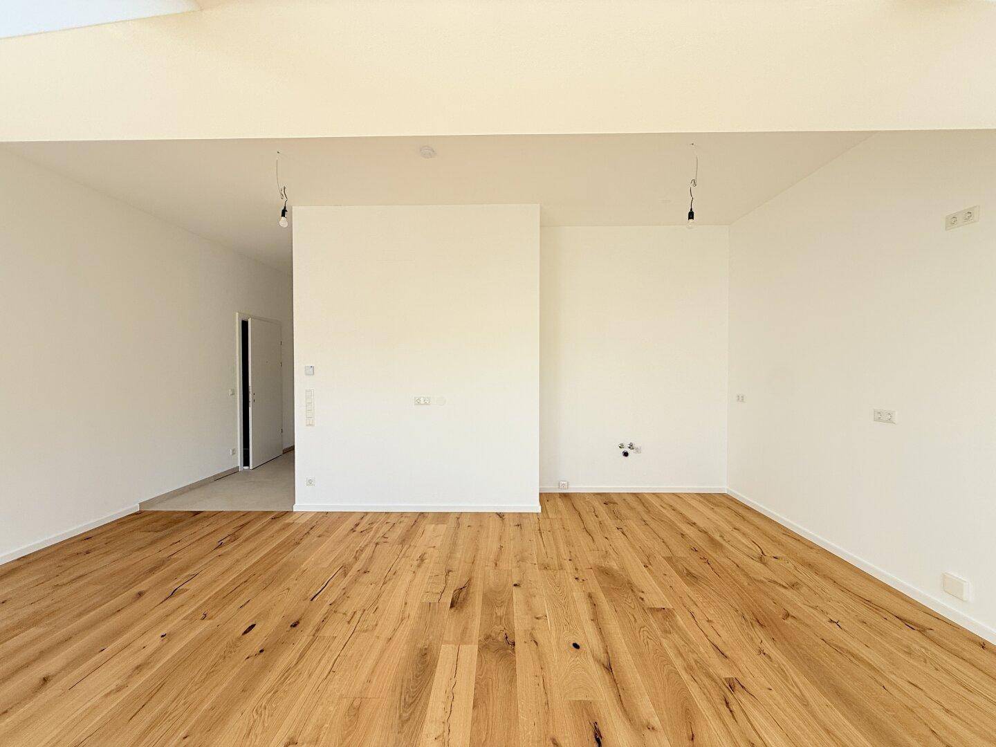 Heller, leerer Raum mit weiß gestrichenen Wänden und Holzboden, bereit für individuelle Gestaltung und Nutzung.