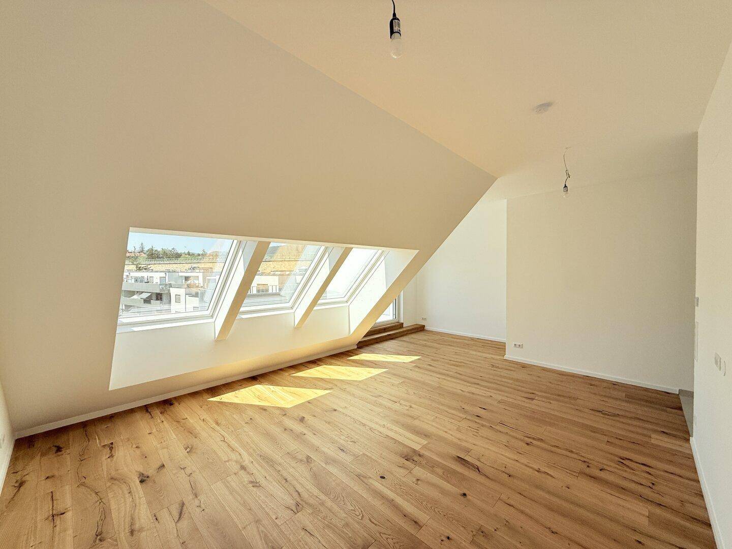 Lichtdurchfluteter Dachgeschossraum mit Holzboden und mehreren Dachfenstern, bietet weite Ausblicke und Helligkeit.