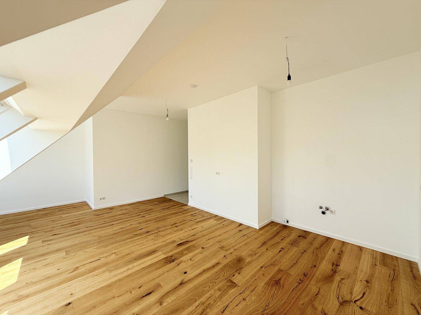 Leerer Raum mit Holzboden und Anschlüssen an der Wand, vielseitig nutzbar und in neuwertigem Zustand.