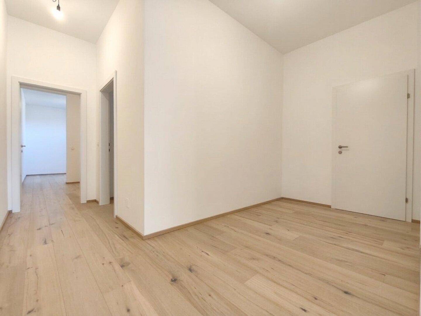 Geräumiger Flur mit Holzboden und mehreren Türen zu angrenzenden Räumen.