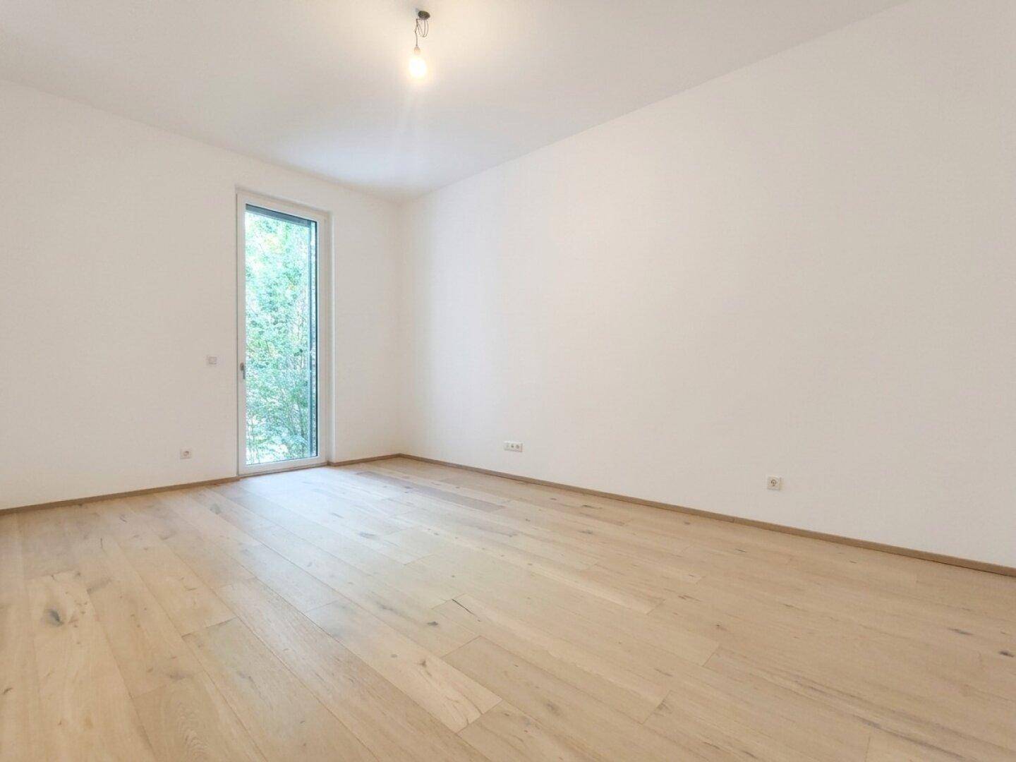 Helles Schlafzimmer mit Holzboden und Zugang zu einem kleinen Außenbereich.