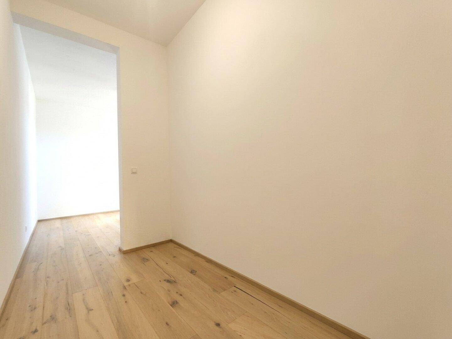 Heller Flur mit Holzboden und weiß gestrichenen Wänden.