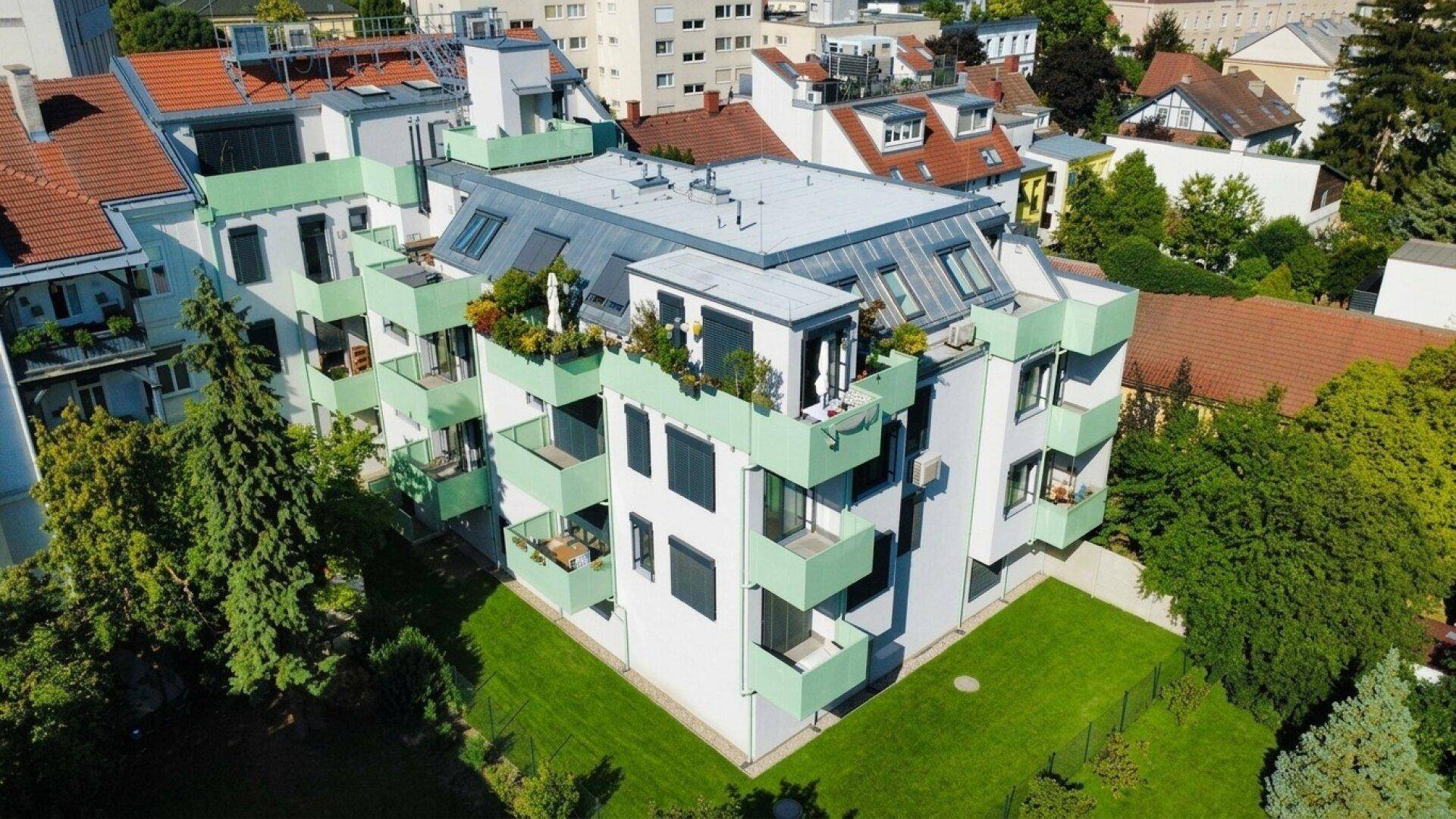 Modernes Wohngebäude mit grünen Balkonen und gepflegter Grünfläche.