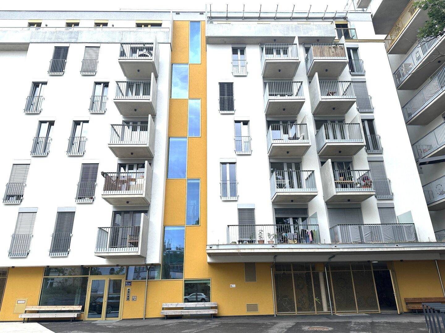 Ansicht der modernen Wohnfassade mit zahlreichen Balkonen und großen Fenstern, gut beleuchtet.