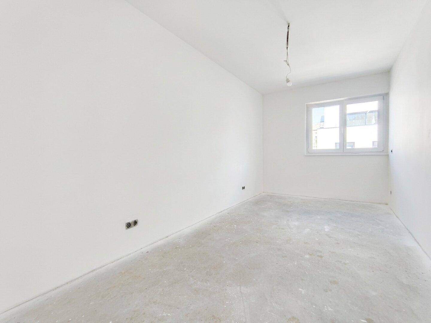 Leerer Raum mit weiß gestrichenen Wänden und einem Fenster, bereit für die individuelle Gestaltung.