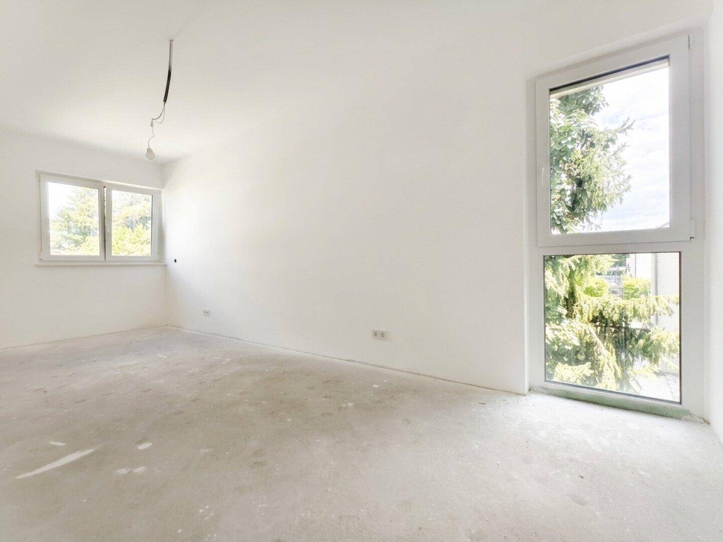 Heller, unmöblierter Raum mit zwei Fenstern und Rohbetonboden, ideal für Schlaf- oder Arbeitszimmer.