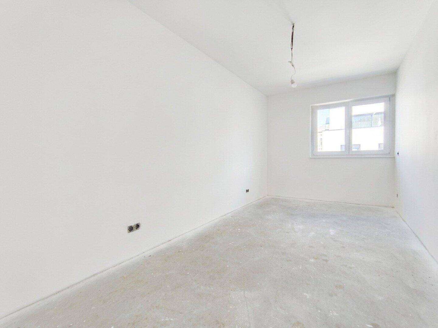 Unmöblierter Raum mit weiß gestrichenen Wänden und einem Fenster, ideal für Schlafzimmer oder Büro.