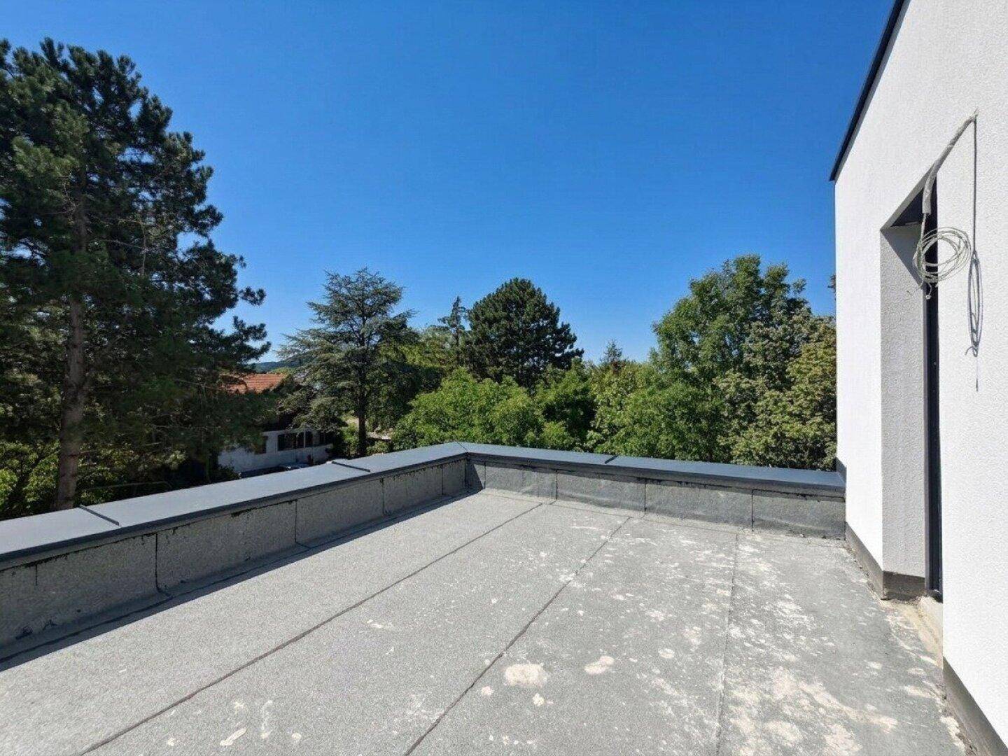 Große, unfertige Dachterrasse mit weitem Blick ins Grüne und blauen Himmel.