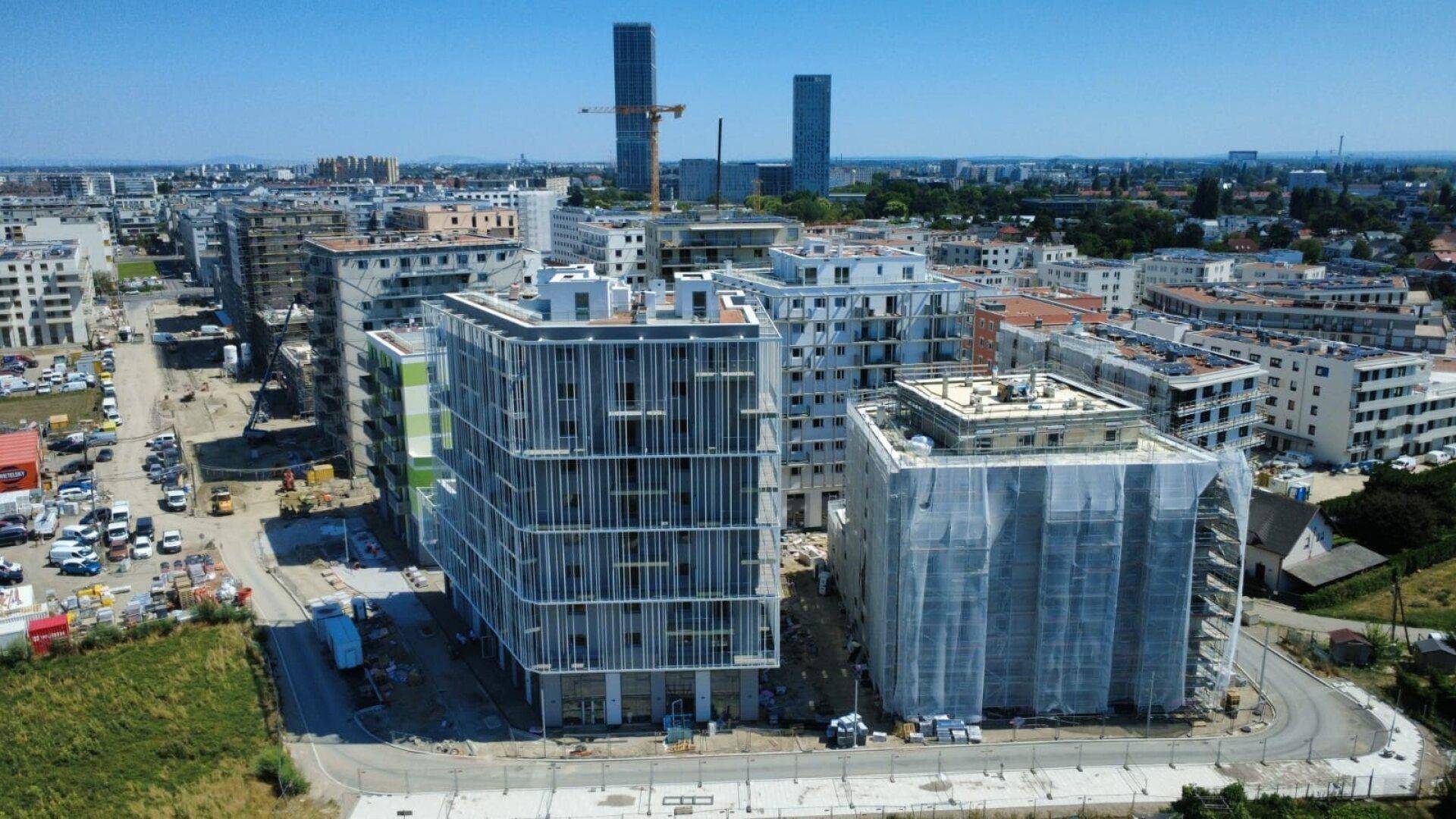 Luftaufnahme eines Neubauprojekts mit modernen Gebäuden und Kränen in der Ferne.
