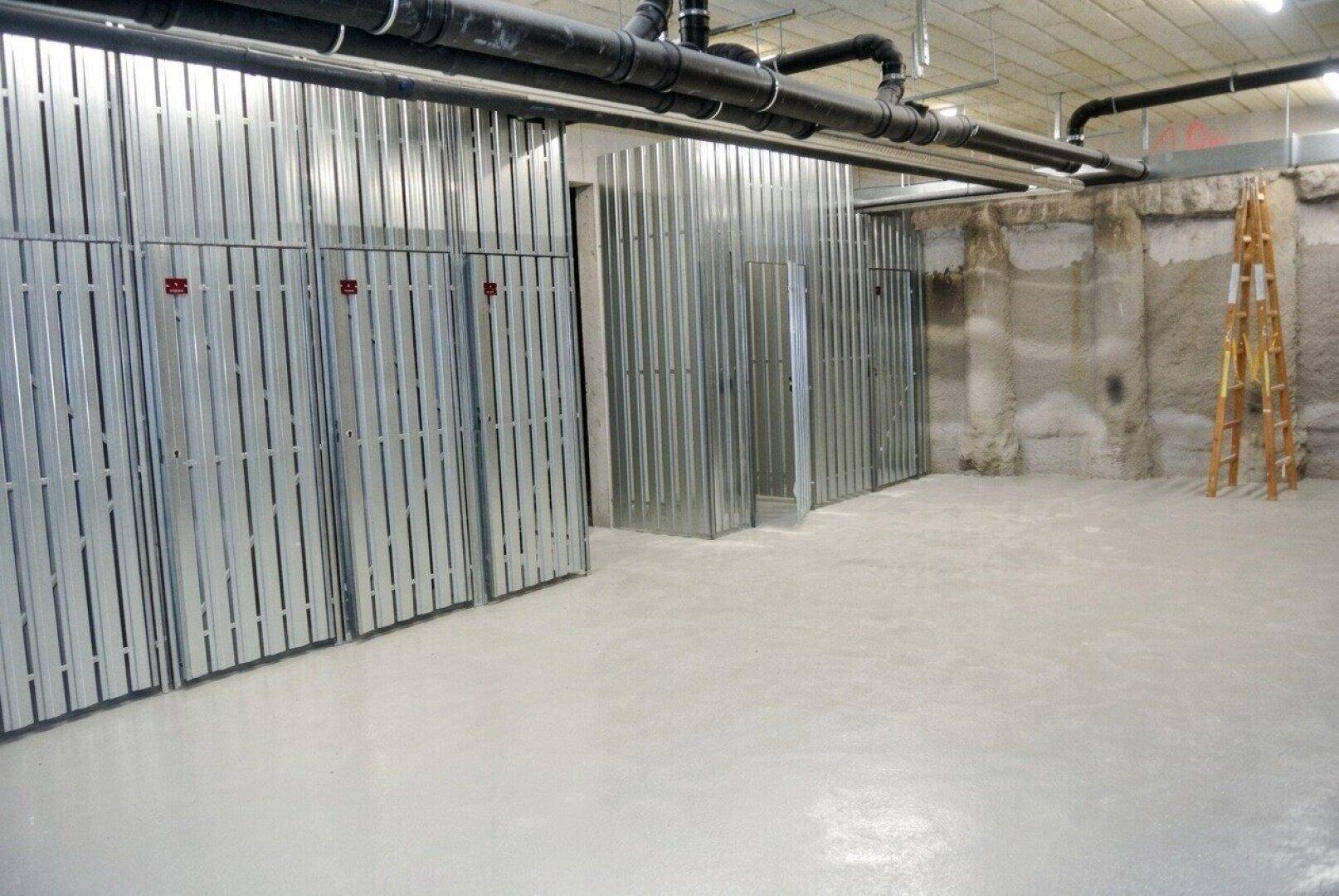 Geräumiger Kellerraum mit individuellen Lagerabteilen aus Metall und sichtbaren Leitungen.