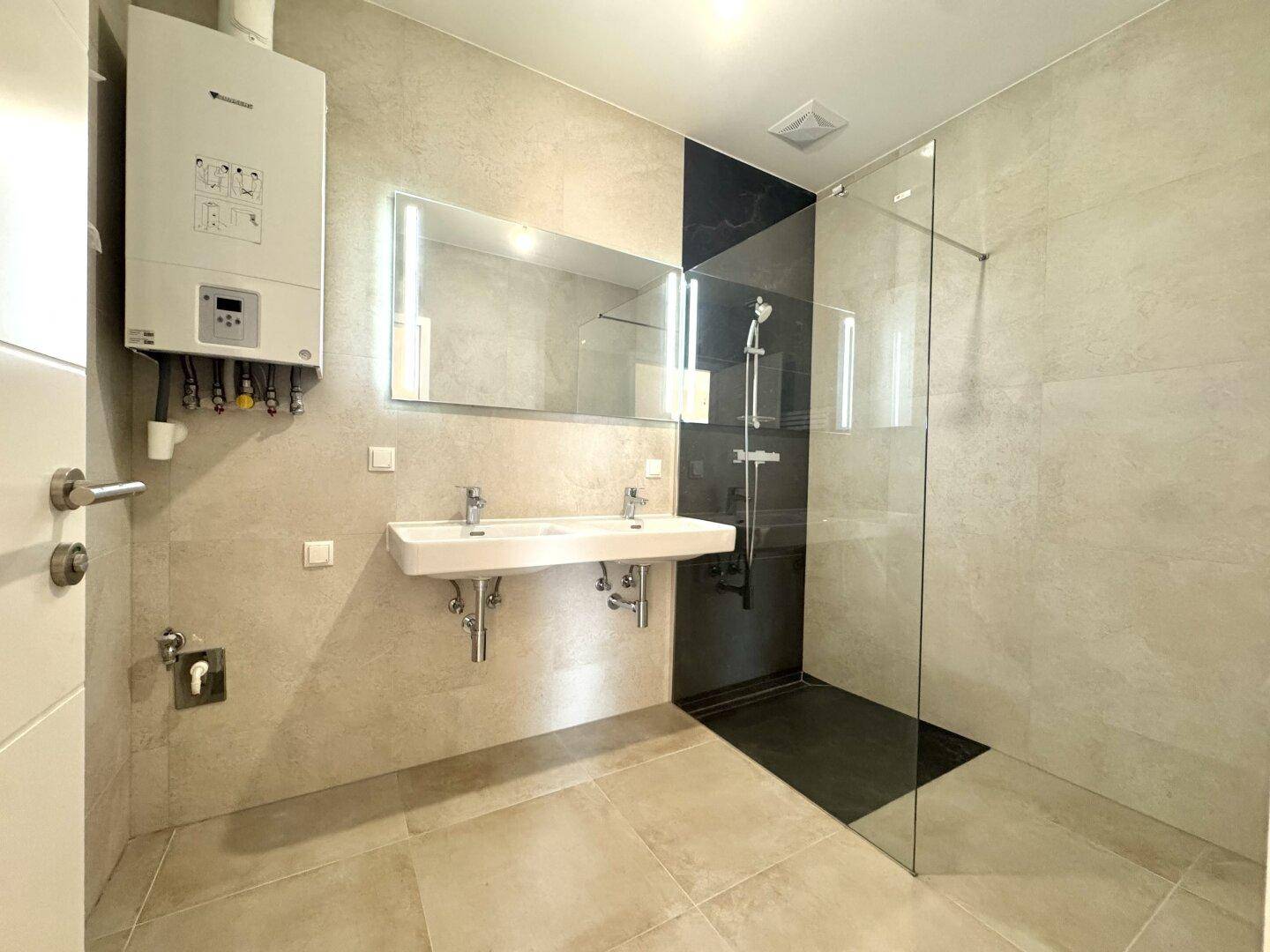 Modernes Badezimmer mit Doppelwaschbecken, großer begehbarer Dusche und Wandheizung.