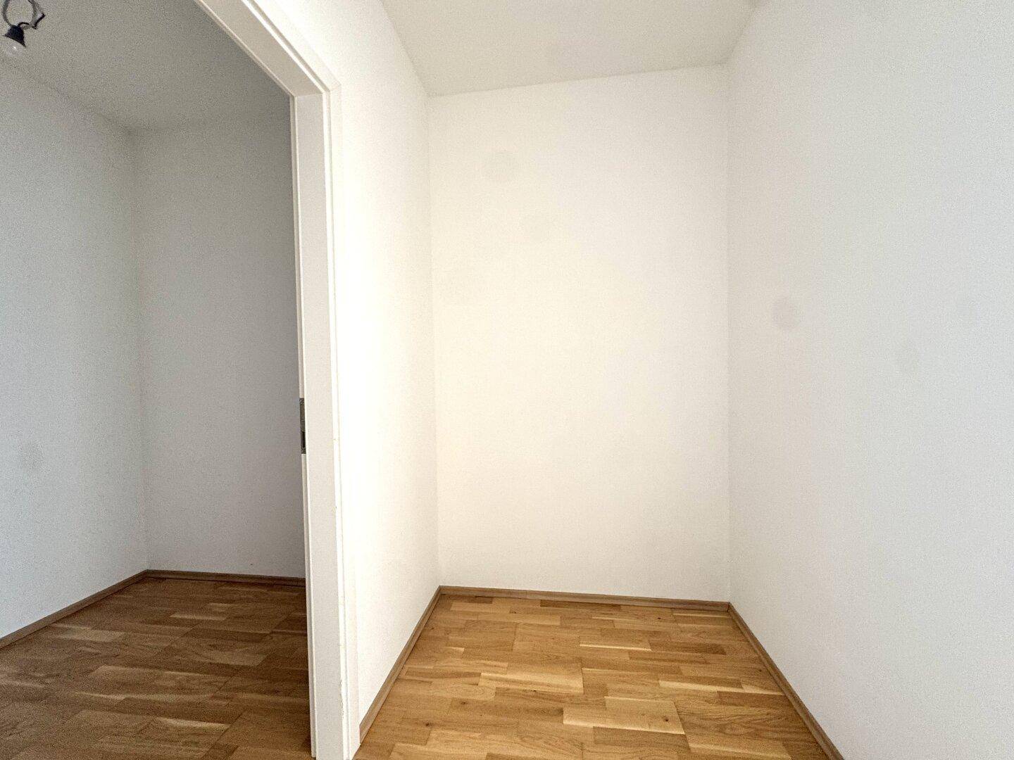 Weiterer kleiner Raum mit Holzboden und weißen Wänden, vielseitig nutzbar als Abstell- oder Ankleidezimmer.