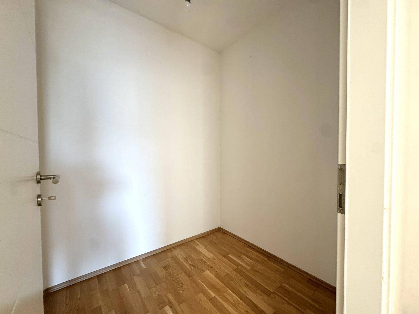 Kleiner Abstellraum mit Holzboden und weißen Wänden, ideal für zusätzlichen Stauraum.