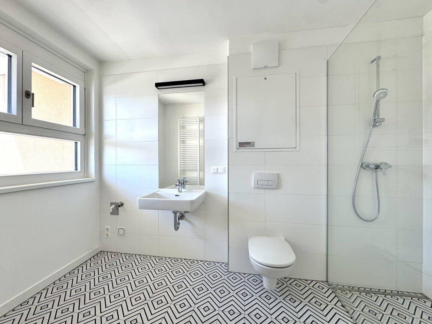 Modernes Badezimmer mit Duschkabine, WC, Waschbecken und Fenster für Tageslicht.