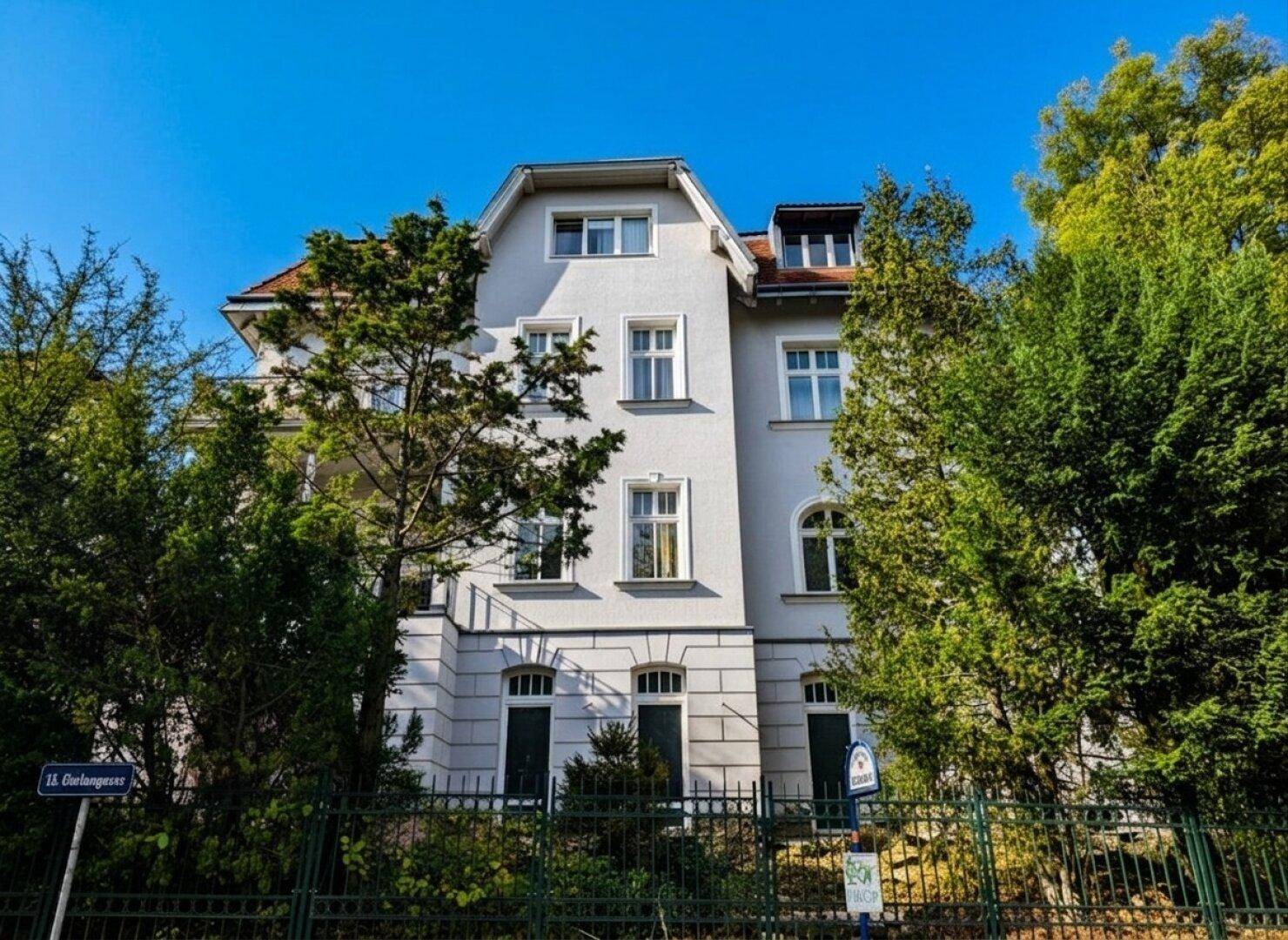Repräsentatives Mehrfamilienhaus mit klassischer Architektur und umgebenden Bäumen.