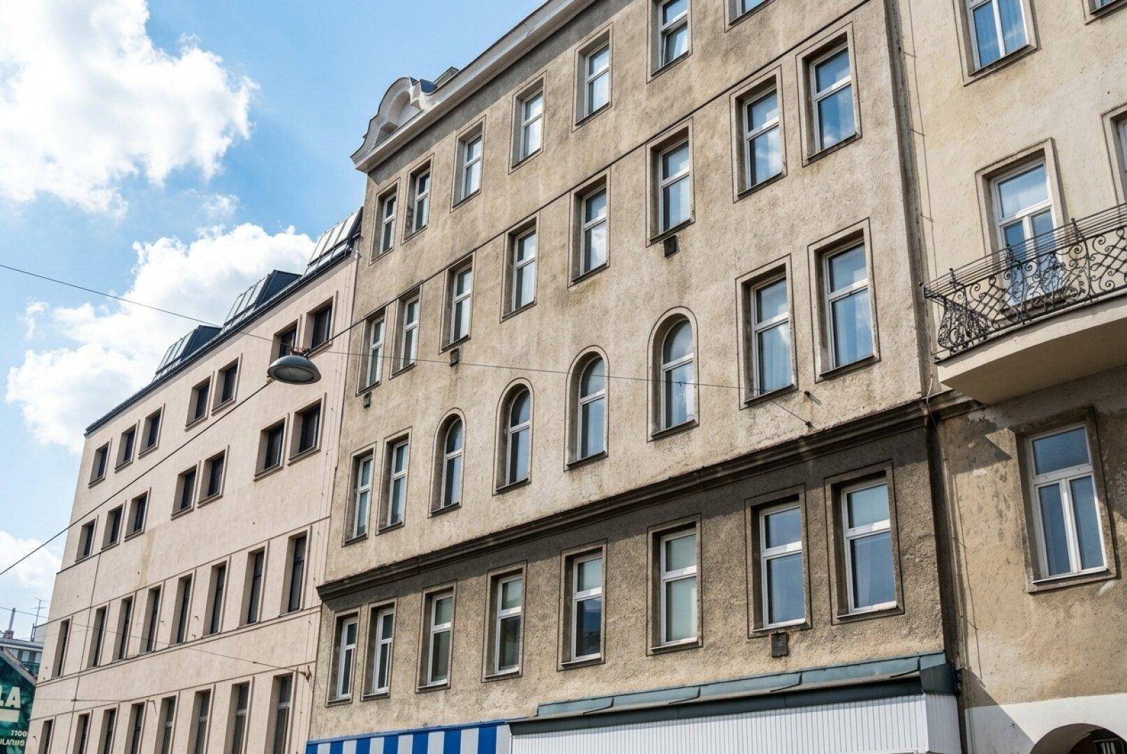 Historische Gebäudefassade mit vielen Fenstern und einem kleinen Balkon mit schmiedeeisernem Geländer.