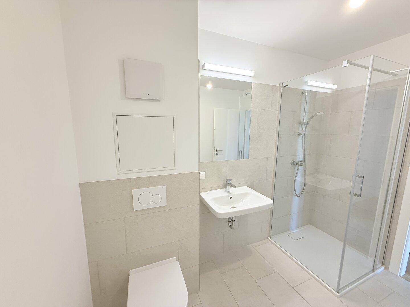 Helles Badezimmer mit Duschkabine, WC und Waschbecken, ausgestattet mit modernen Armaturen.