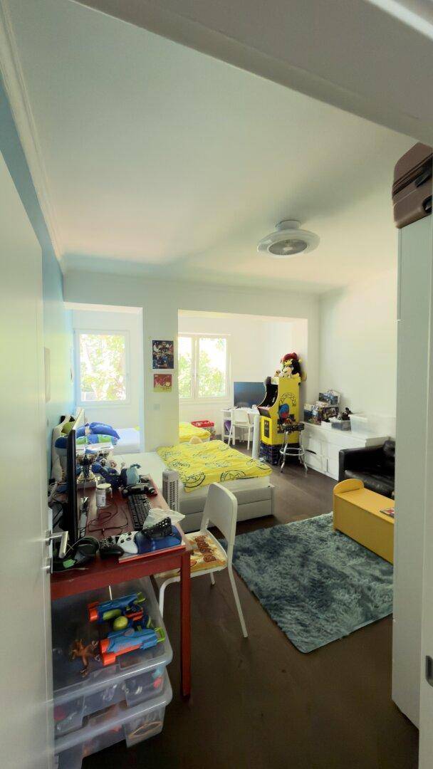 Helles Kinderzimmer mit Bett, Schreibtisch und Spielautomaten, ideal zum Schlafen und Spielen.