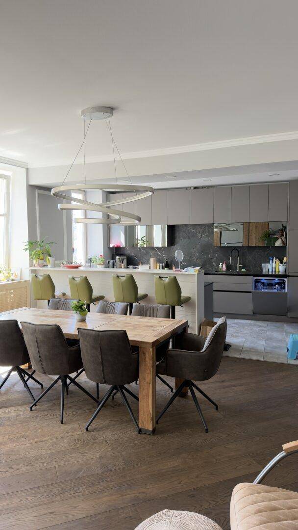 Moderne offene Küche mit Kücheninsel, Essbereich und dunklem Holzboden.