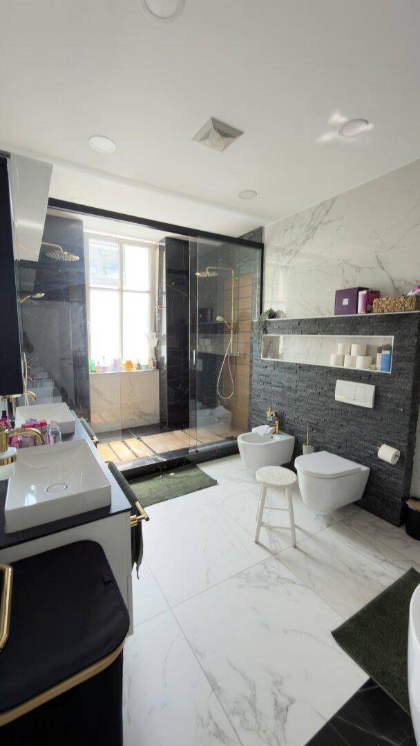 Luxuriöses Badezimmer mit großer begehbarer Dusche, Doppelwaschbecken und Marmorfliesen.