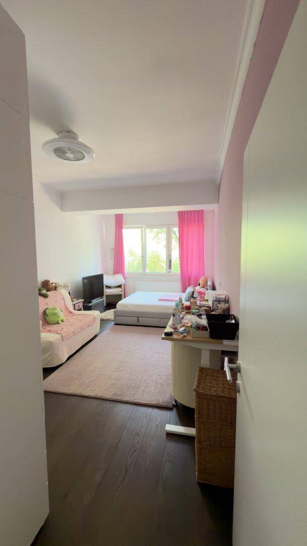 Helles Kinderzimmer mit Einzelbett, Sofa und rosa Vorhängen, bietet Platz zum Entspannen.