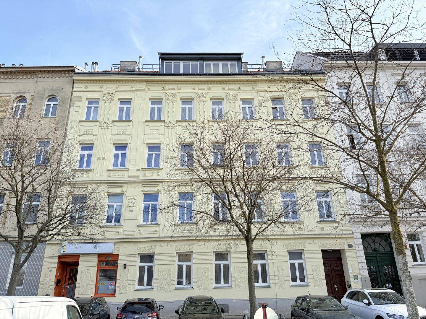 Klassische Fassade eines Mehrfamilienhauses mit vielen Fenstern und Balkonen.