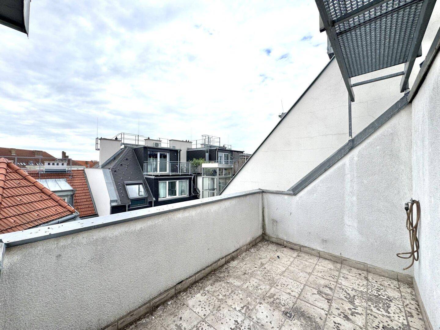 Dachterrasse mit Blick auf umliegende Gebäude und den Himmel, bereit zur individuellen Gestaltung.