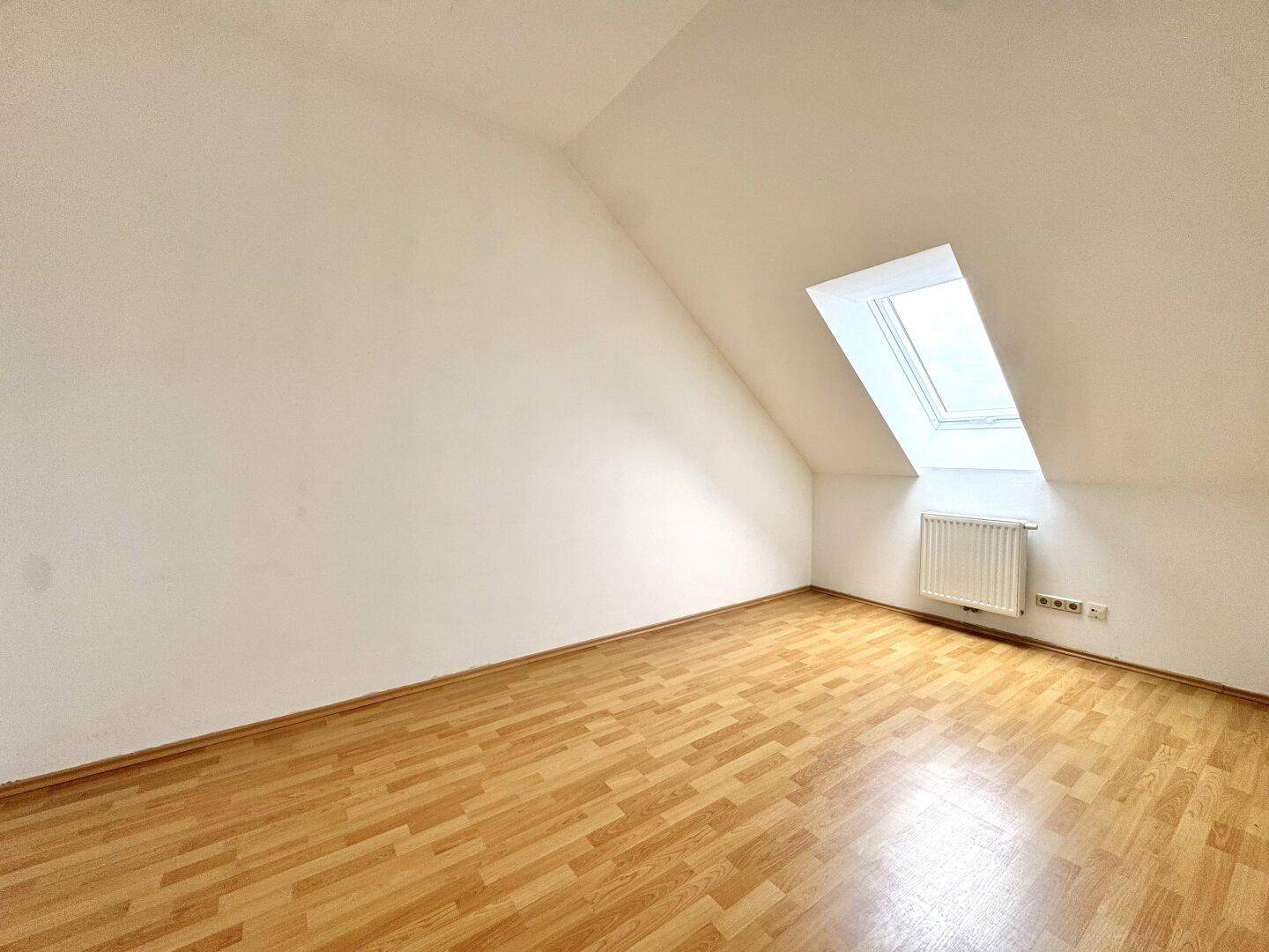 Helles Zimmer mit Laminatboden und Dachfenster, bietet viel Tageslicht und Ruhe.
