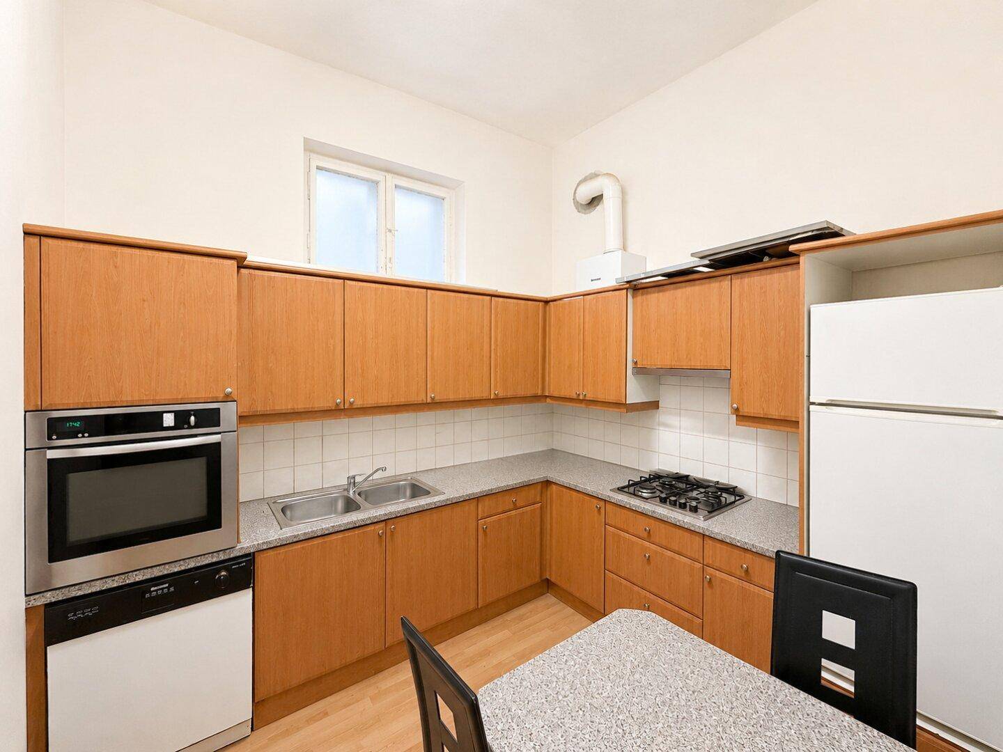 Funktionale Küche mit Holzschränken, Gasherd, Backofen und Essbereich für Mahlzeiten.