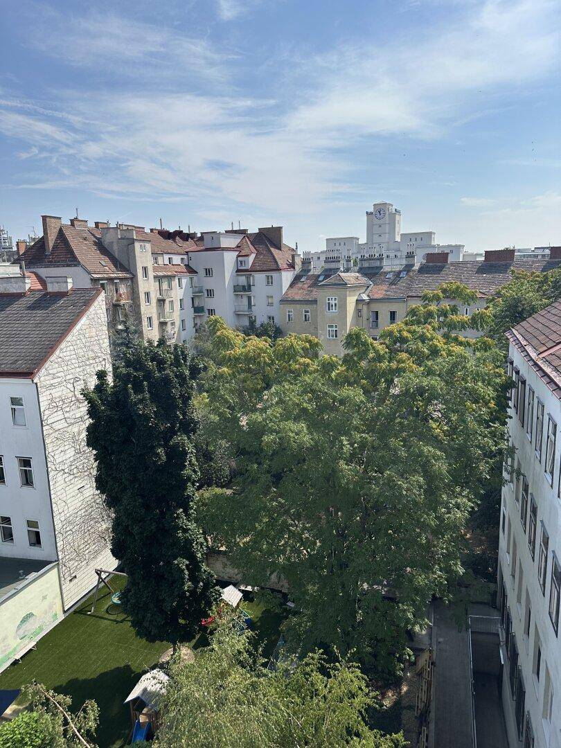 Panoramablick über die Dächer der Stadt mit grünen Bäumen und einem Spielplatz im Innenhof.
