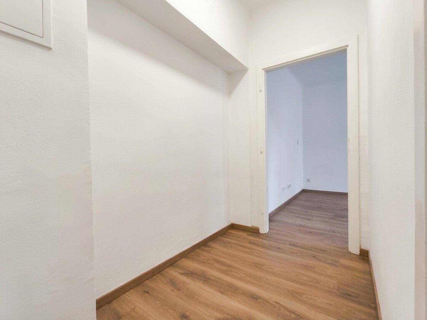 Heller Flur mit Laminatboden und Zugang zu den Wohnräumen der Wohnung.