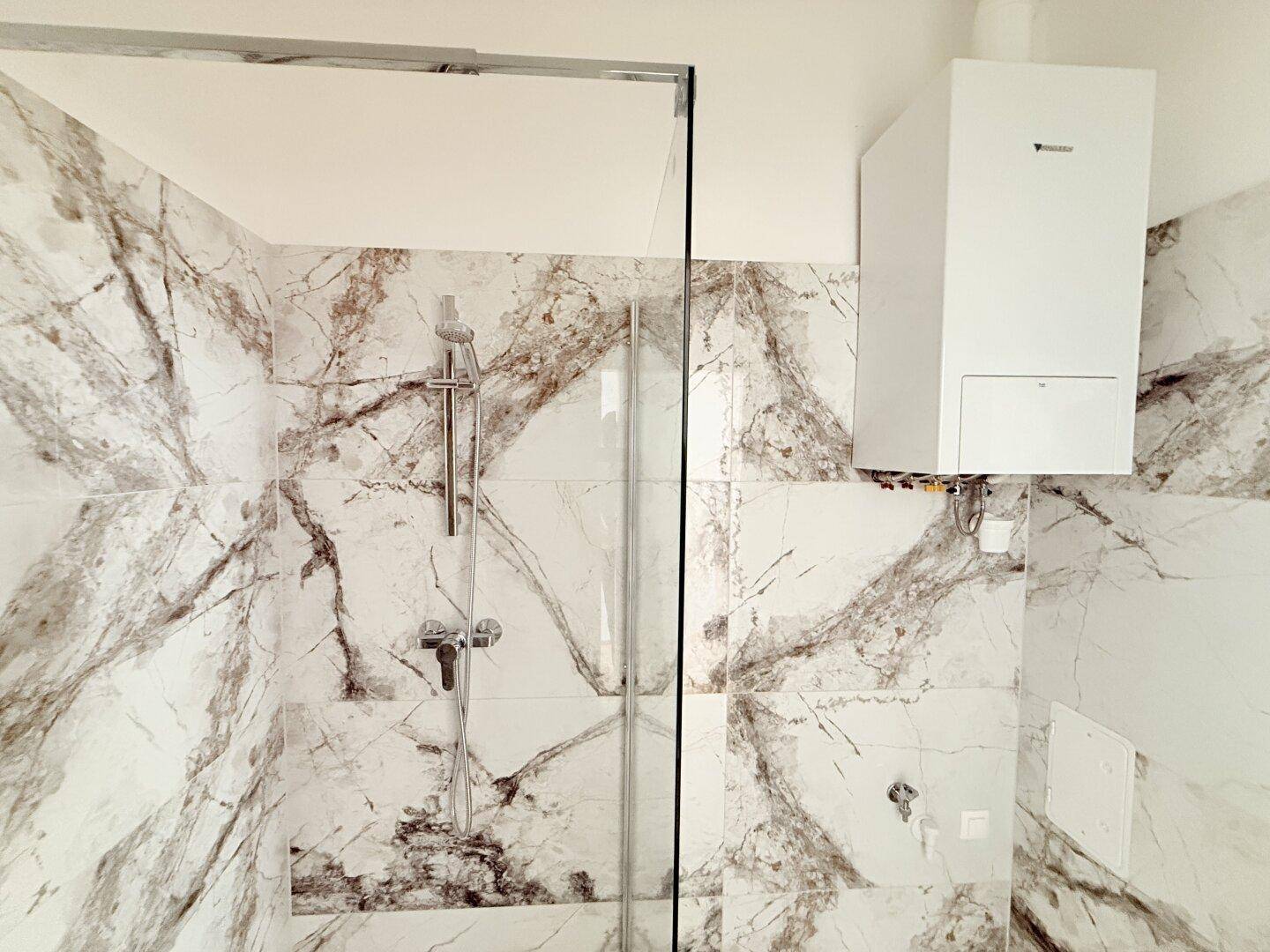 Detailansicht der begehbaren Dusche und des Warmwasserbereiters im modernen Badezimmer.
