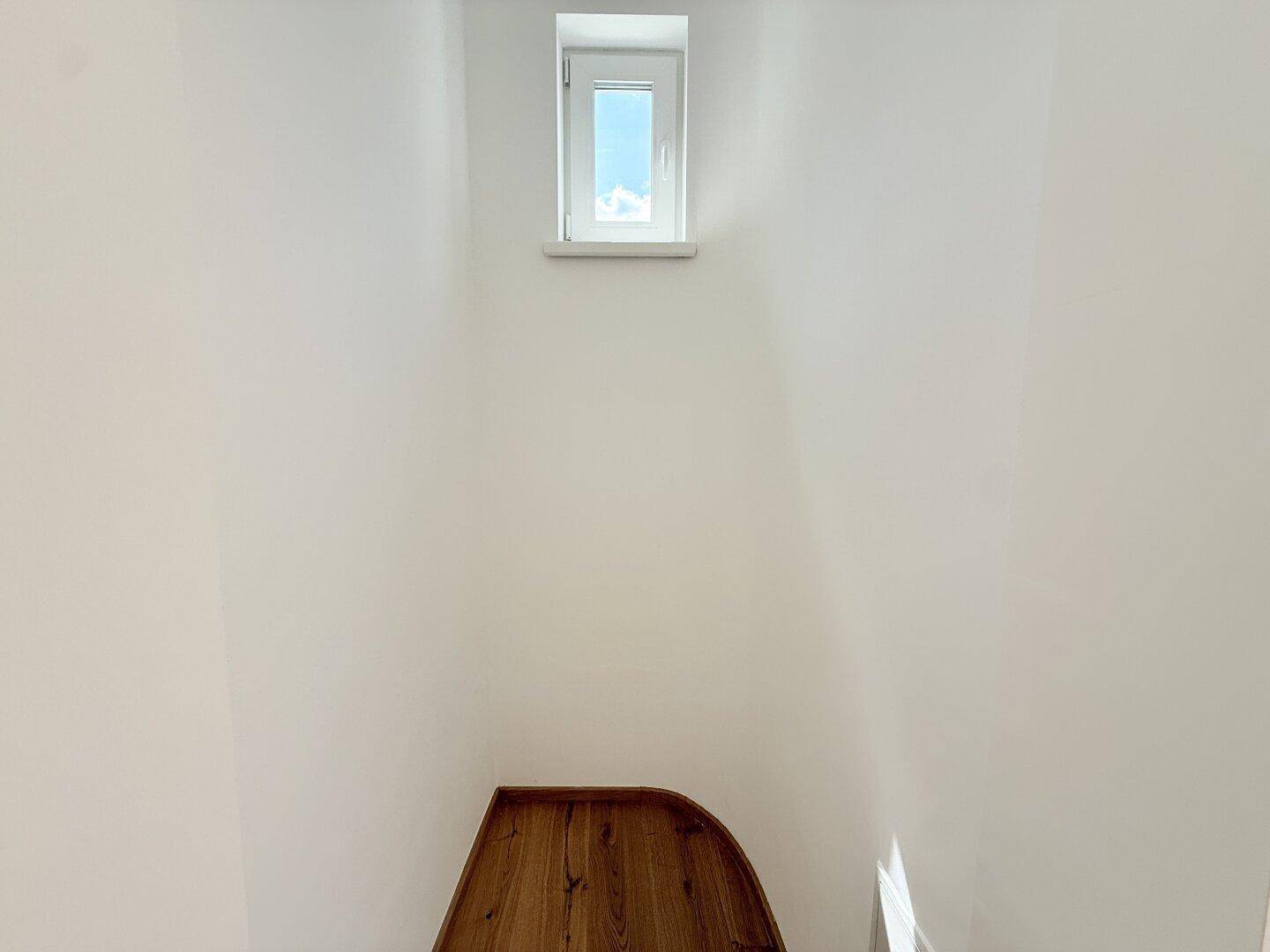 Kleiner Raum mit Holzboden und einem hochgelegenen Fenster, ideal als Abstellraum.