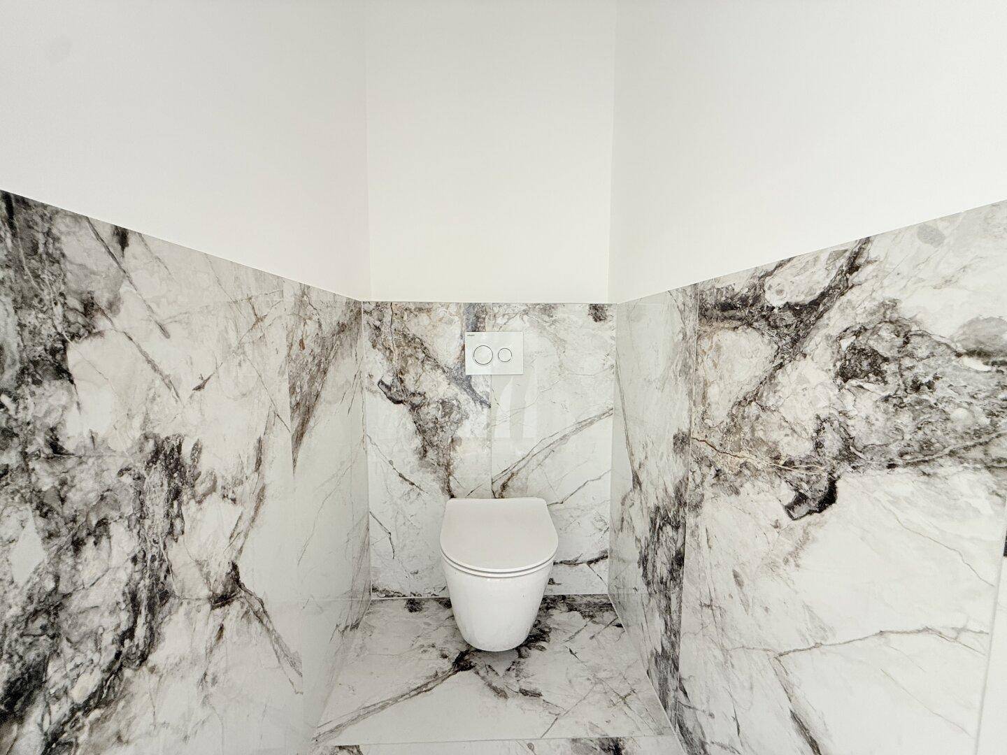 Modernes WC mit eleganten Marmorfliesen und wandhängender Toilette.