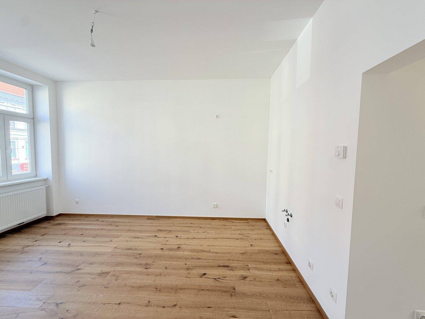 Leerer Raum mit Holzboden und einem Fenster, bietet flexible Nutzungsmöglichkeiten.