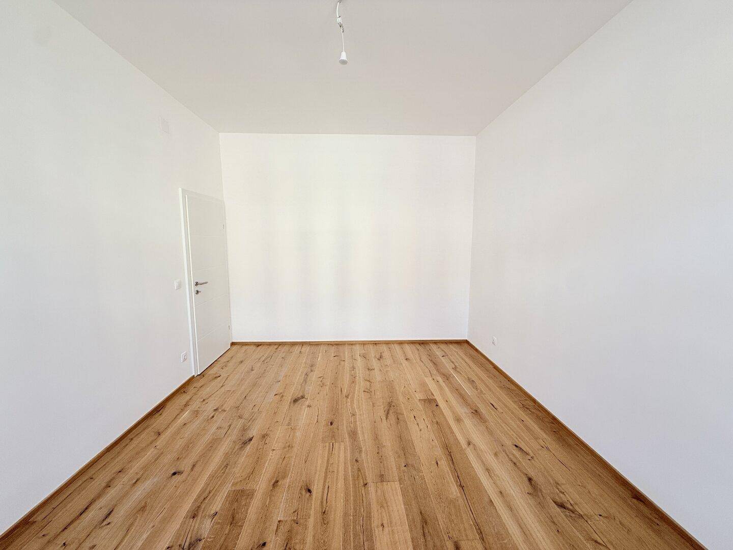 Leerer Raum mit Holzboden und weiß gestrichenen Wänden, bietet flexible Nutzung.