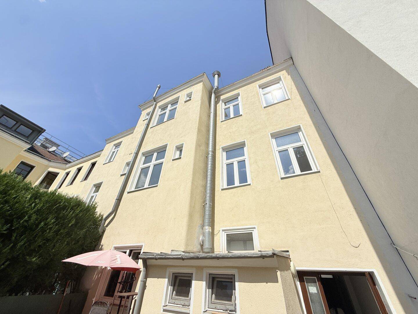 Rückfassade eines Gebäudes mit mehreren Fenstern und einem Blick auf den Innenhof.