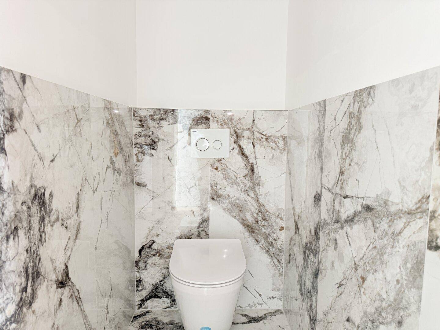 Modernes WC mit eleganten Marmorfliesen und wandhängender Toilette, stilvoll und funktional.