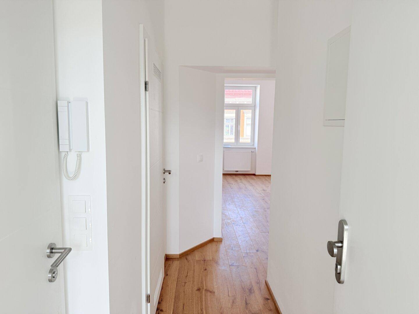 Eingangsbereich mit Gegensprechanlage und Blick in den hellen Flur, einladend gestaltet.